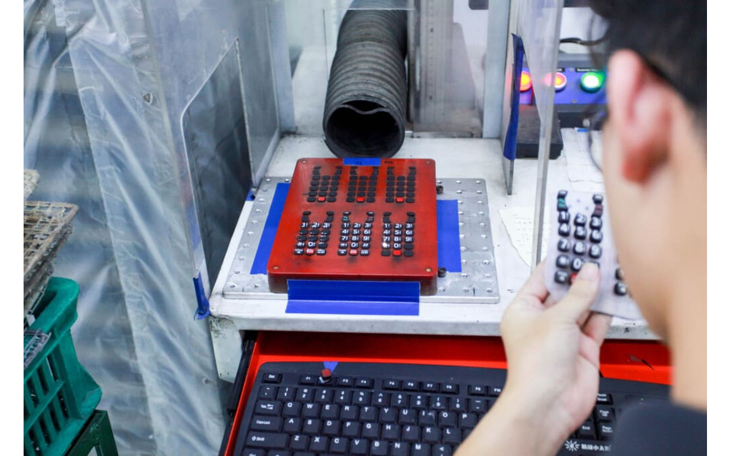 Close-up view of laser ablation creating translucent graphic icons on a backlit silicone keypad.