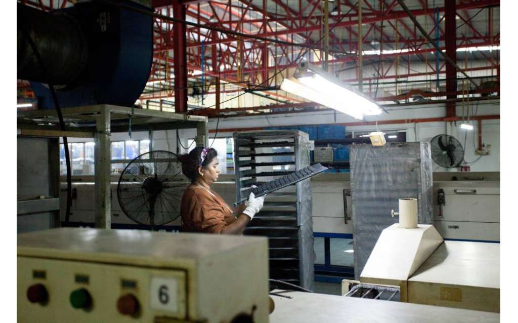 Final visual inspection checking the printing condition of rubber components immediately after leaving the drying conveyor oven.
