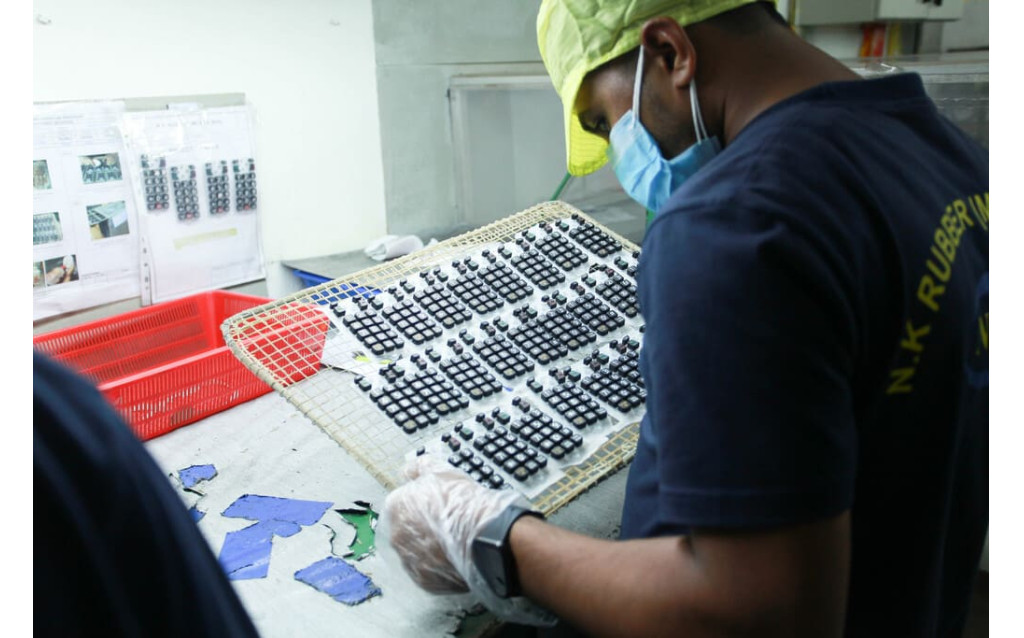 Quality assurance inspector checking the condition and precision tolerances of laser-etched backlit graphics.