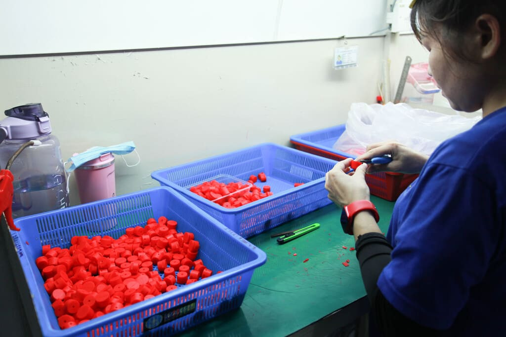 Assembly technicians integrating custom rubber seals into metal housings at specialized workstations.