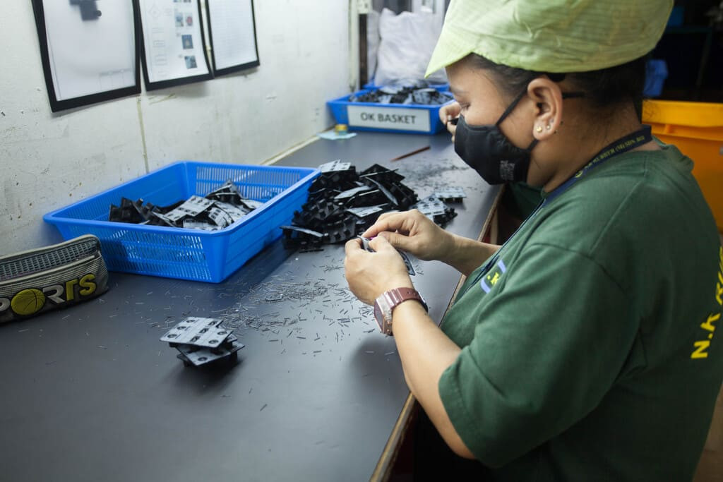 In-line quality control inspection checking dimensional tolerances of assembled rubber-to-plastic parts.