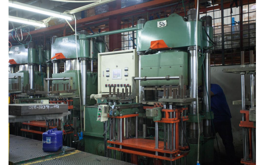 Careful demolding and extraction of newly cured rubber components from the press.