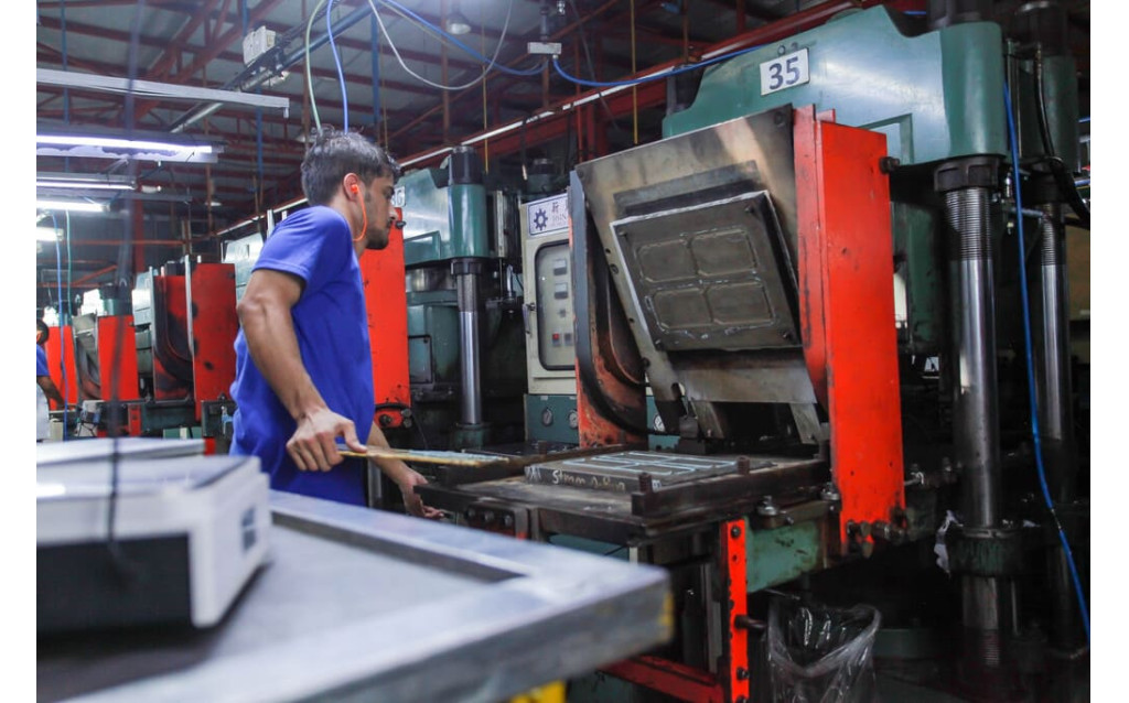 A line of heavy-duty hydraulic compression moulding presses on the factory floor.